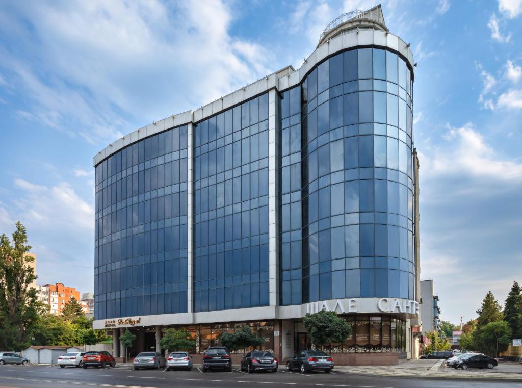 a glass office building with cars parked in front of it at Red Royal by Undersun in Krasnodar