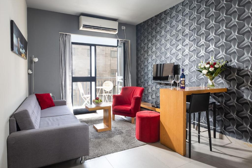 un soggiorno con divano e scrivania con TV di Hillel 11 Hotel a Gerusalemme