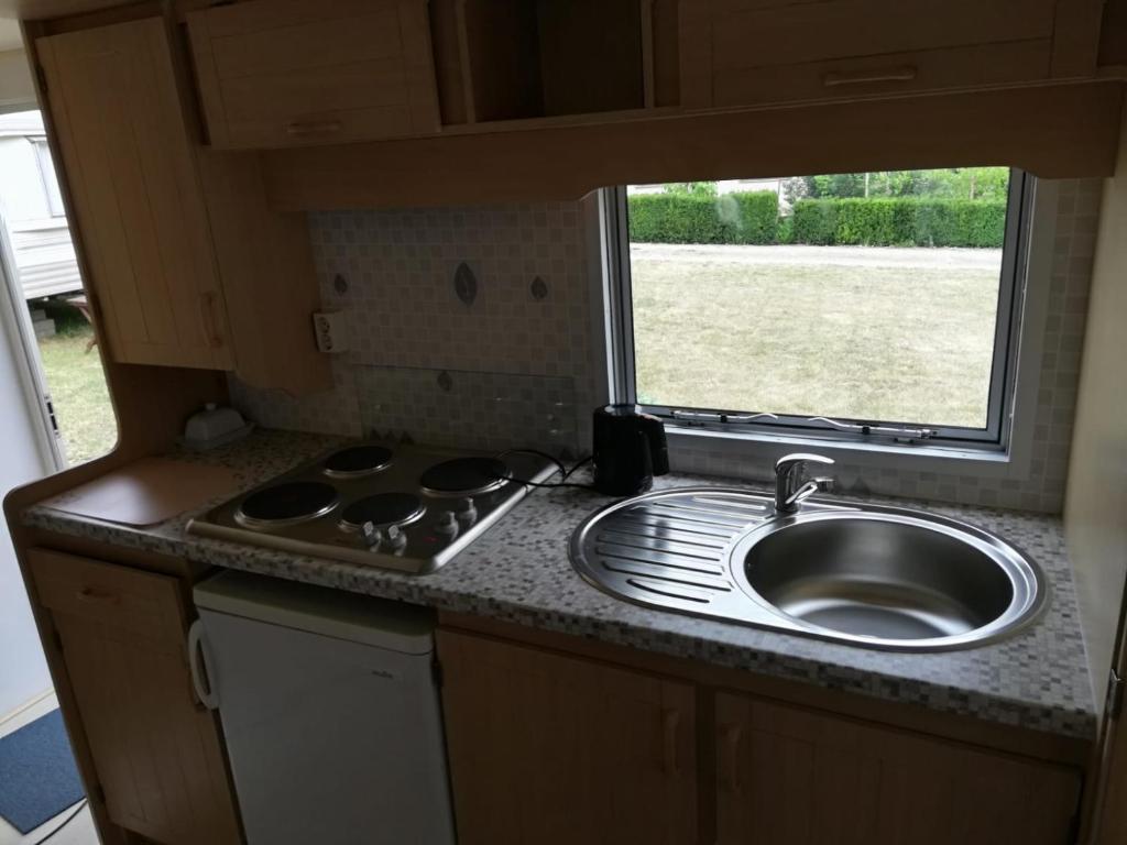 uma pequena cozinha com um lavatório e uma janela em Domki obok plaży em Moryń