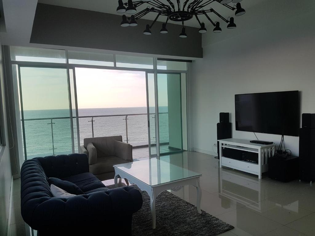 uma sala de estar com um sofá, uma televisão e uma mesa em Bay Resort Condominium, 7, Beach-front Sea view, 6-8 PAX em Miri