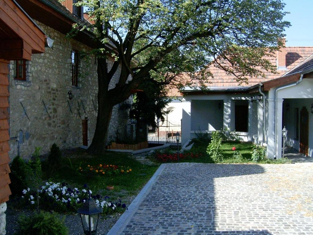 Una pasarela de ladrillo frente a una casa con un árbol en Trifecta Udvarház, en Tállya