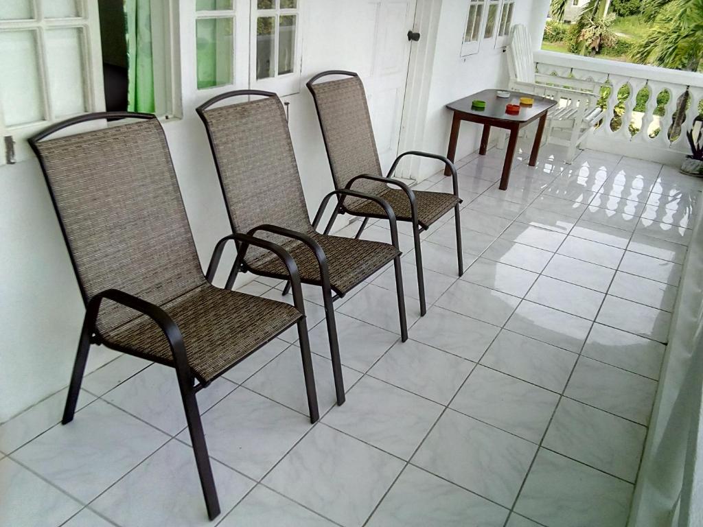 vier stoelen en een tafel op een veranda bij Porty Hostel in Port Antonio