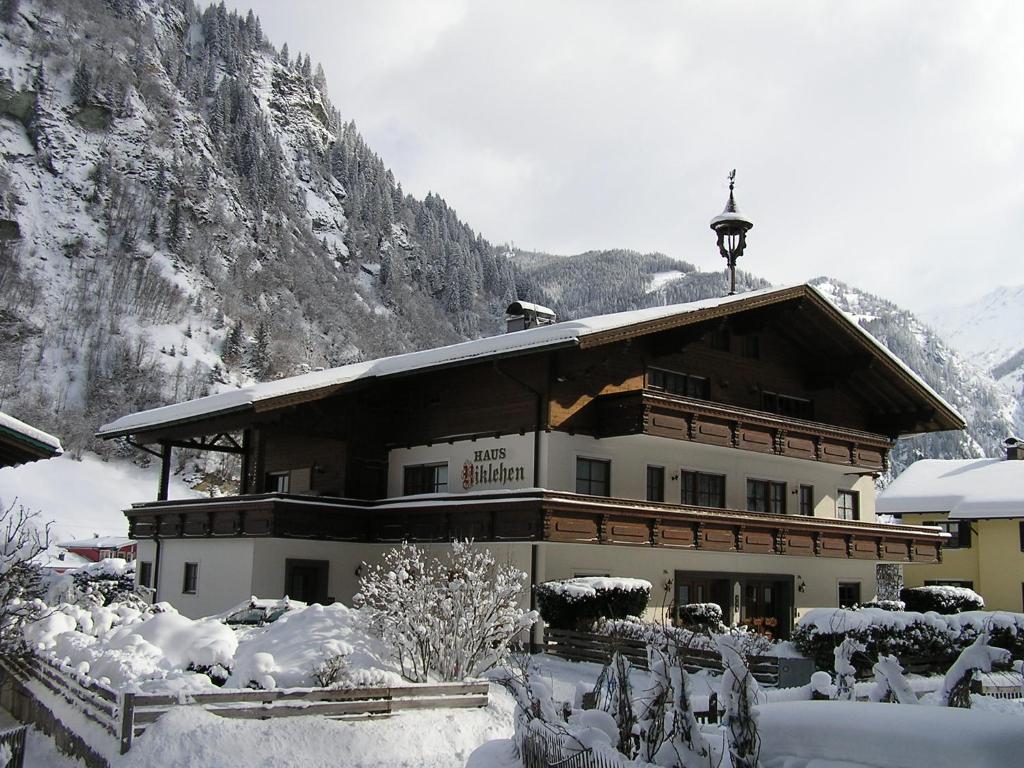un grande edificio nella neve con una montagna di Haus Niklehen a Hüttschlag