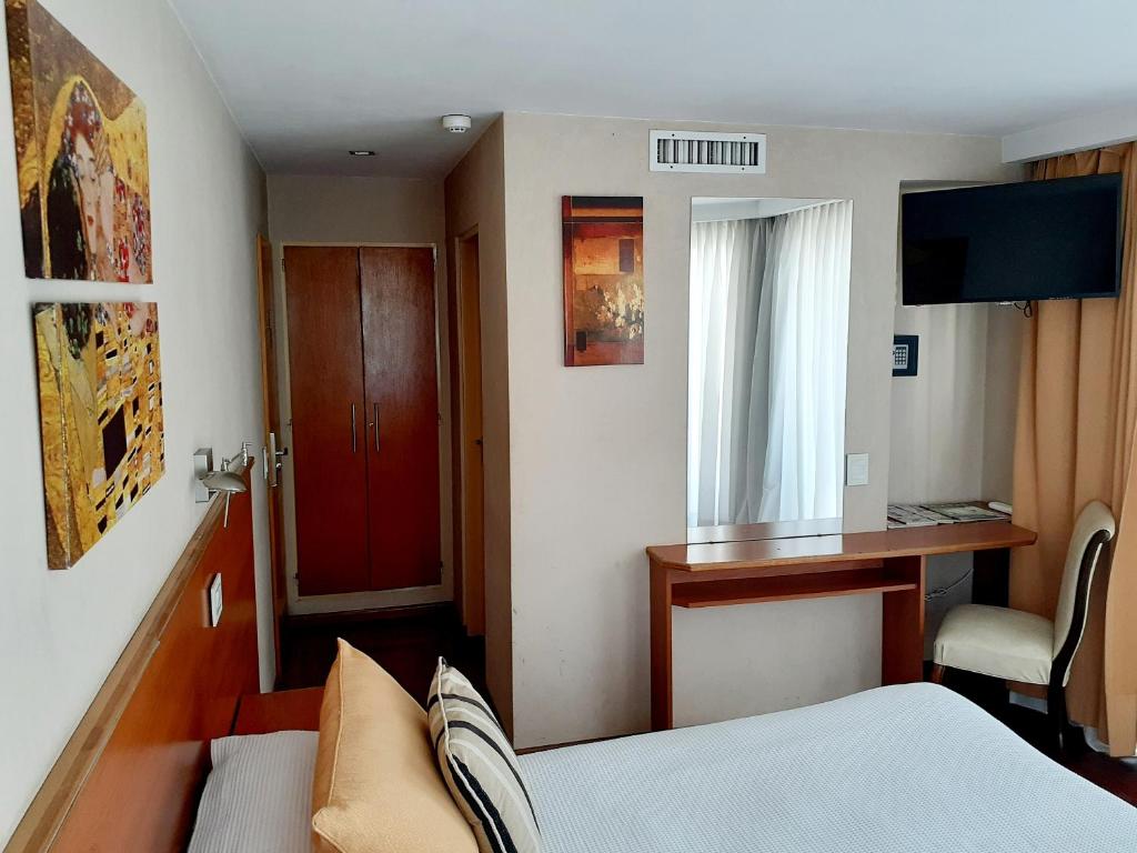 Habitación pequeña con cama y puerta roja en Hotel Benevento en La Plata