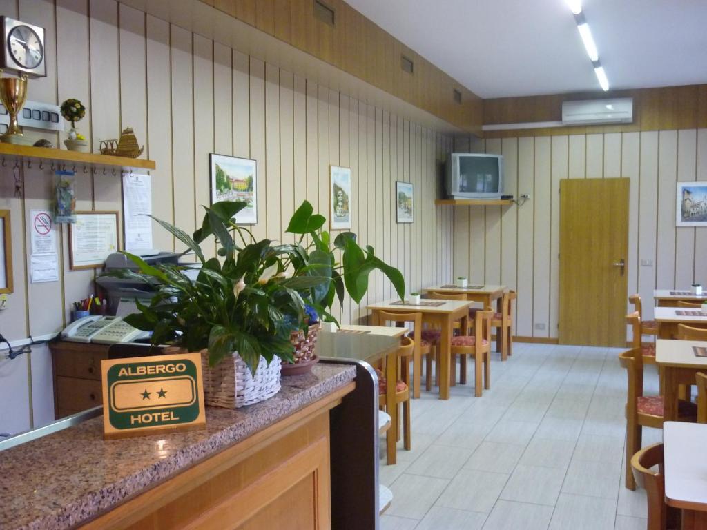 a dining room with tables and chairs and a counter at Hotel Milano in Como