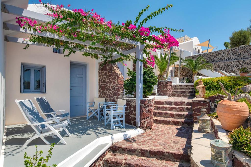 una villa con patio arredato con sedie e fiori di Akrotiri Hotel ad Akrotírion