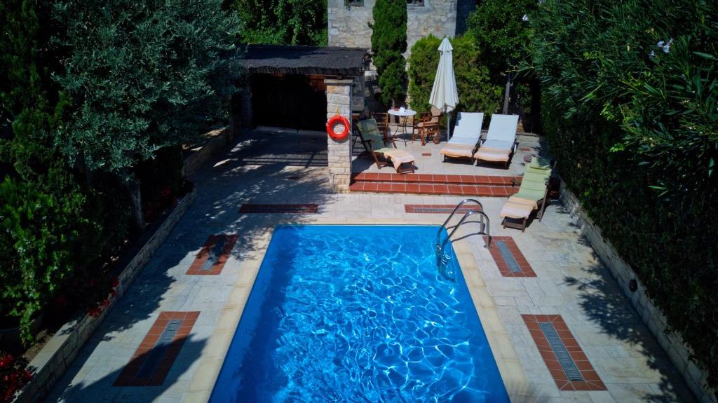 una piscina con una mesa, una sombrilla y un perro en Katsaneiko Mansion, en Afitos