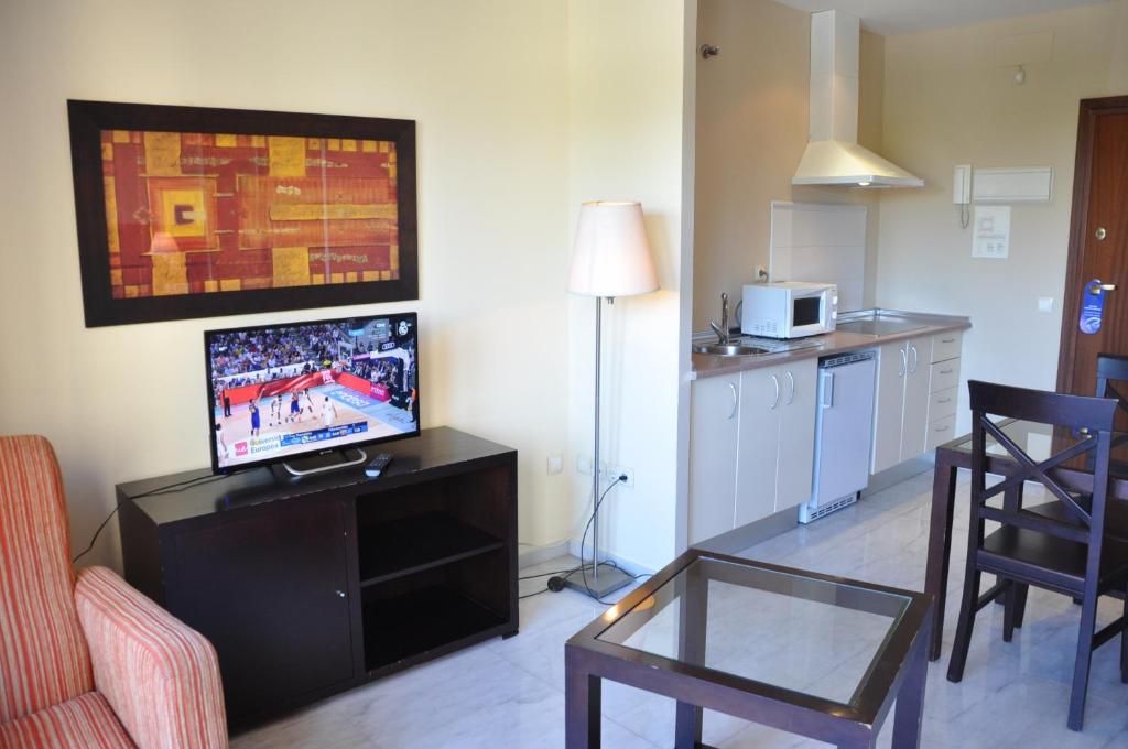 sala de estar con TV, mesa y sillas en Apartamentos Luxsevilla Palacio, en Sevilla