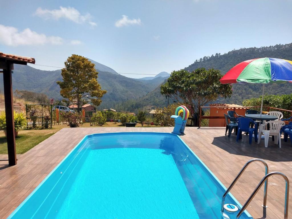 uma piscina com uma mesa e um guarda-sol em Temporada no Paraíso em Teresópolis em Teresópolis