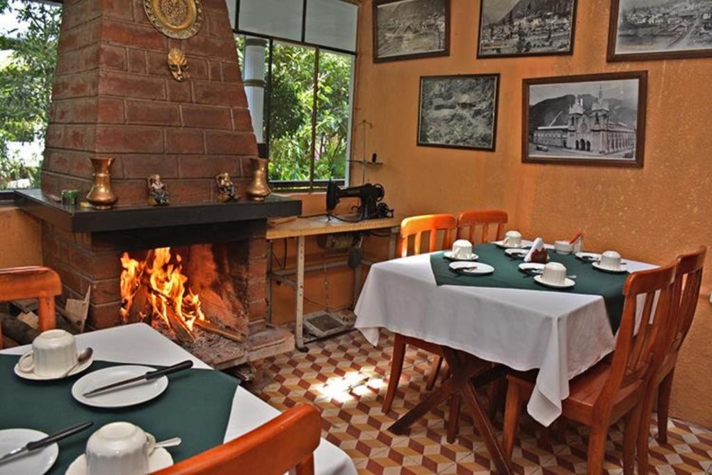El Pedron Hotel في بانوس: غرفة طعام مع طاولة ومدفأة