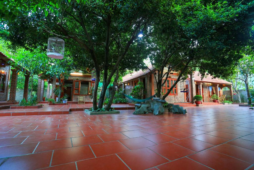 un parco con alberi e pavimento piastrellato rosso di Tam Family Homestay a Ninh Binh