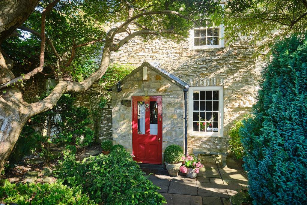 Nuns Cottage Bed & Breakfast في ريتشموند: بيت حجري وباب احمر وشجر