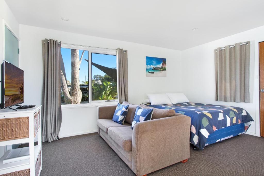 a bedroom with a bed and a couch and a tv at Huskisson Holiday Motel Cabins in Huskisson