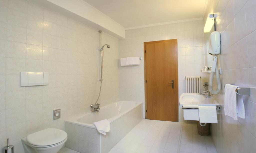 łazienka z wanną, toaletą i umywalką w obiekcie Hotel Dolomiti Madonna w mieście Ortisei