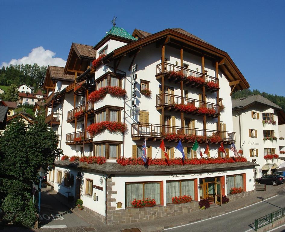 duży biały budynek z flagami w obiekcie Hotel Dolomiti Madonna w mieście Ortisei
