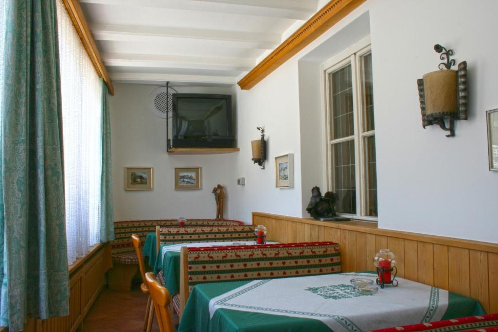 Pokój z dwoma stołami i telewizorem na ścianie w obiekcie Hotel Dolomiti Madonna w mieście Ortisei