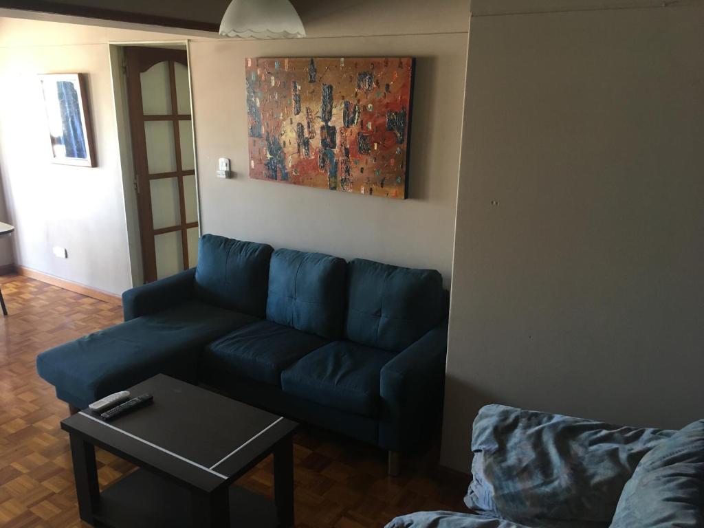un sofá azul en una sala de estar con una pintura en Departamento Aconcagua en Mendoza