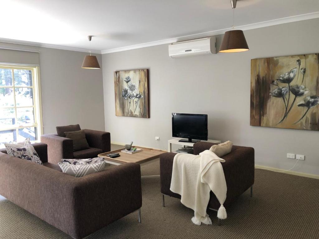 a living room with two couches and a tv at The Old Coolstore - Jonathon Apartment in Merricks North