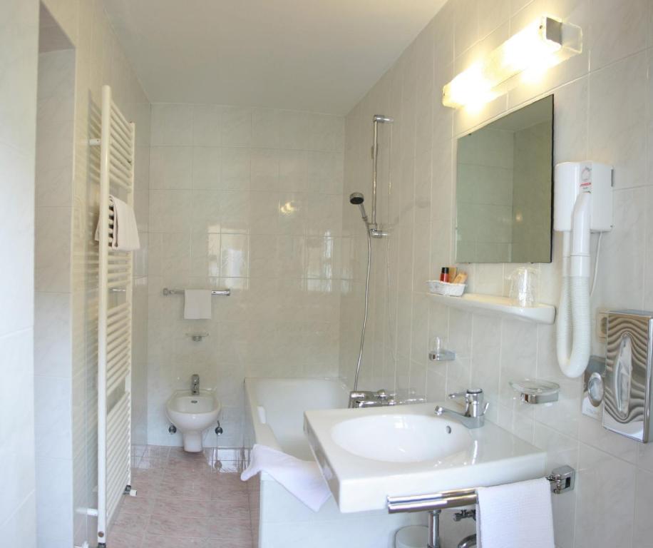 biała łazienka z umywalką i toaletą w obiekcie Hotel Dolomiti Madonna w mieście Ortisei