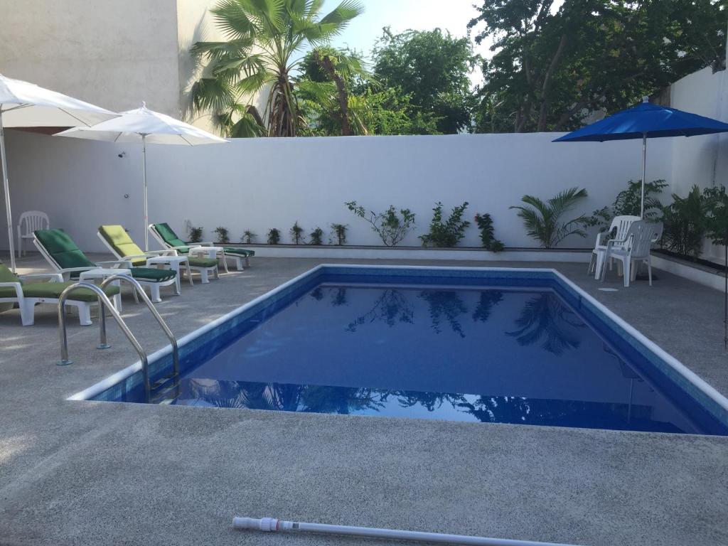 a swimming pool with chairs and an umbrella next to a building at DEPARTAMENTOS LALO in Zihuatanejo