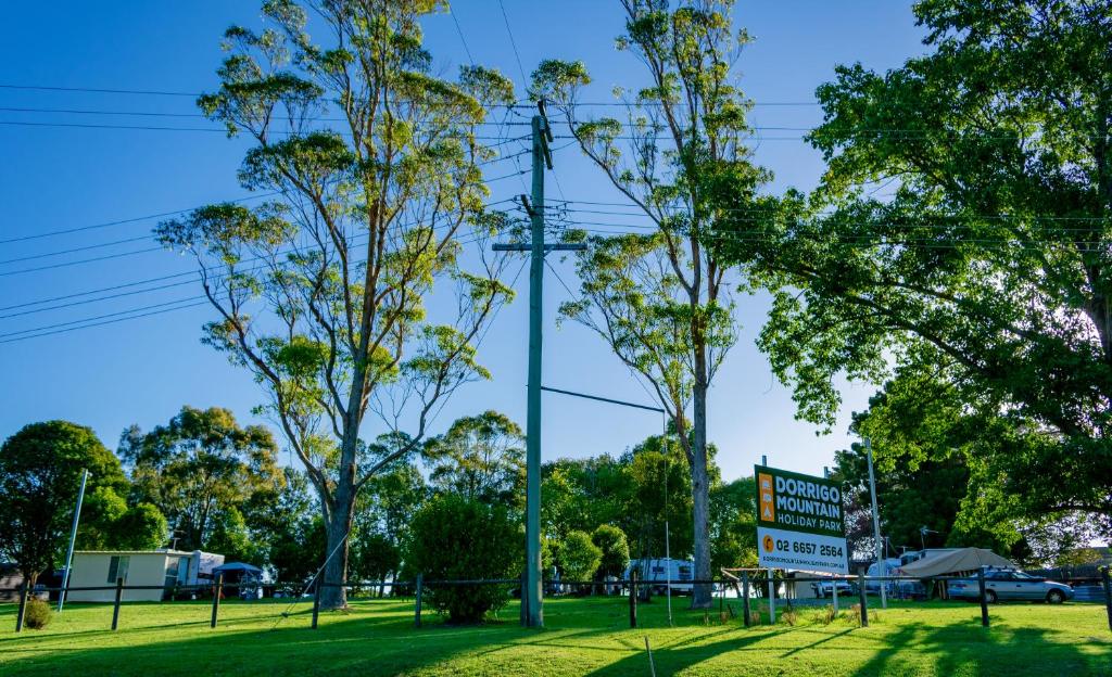 a park with trees and a sign in the grass at Dorrigo Mountain Holiday Park in Dorrigo