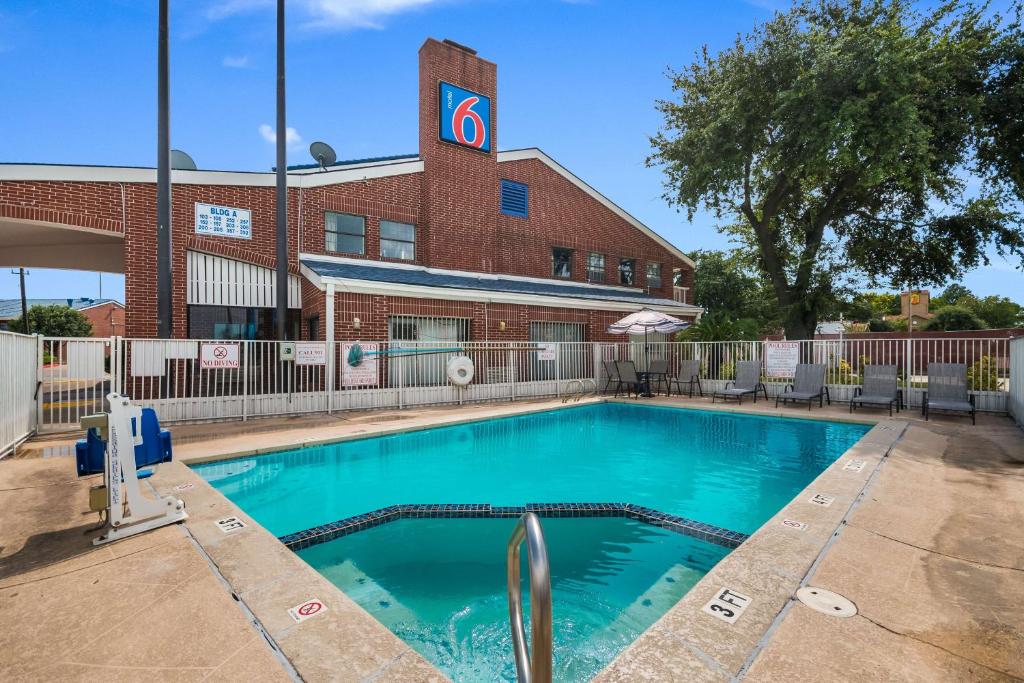 - une piscine en face d'un bâtiment en briques dans l'établissement Motel 6-Houston, TX - Brookhollow, à Houston