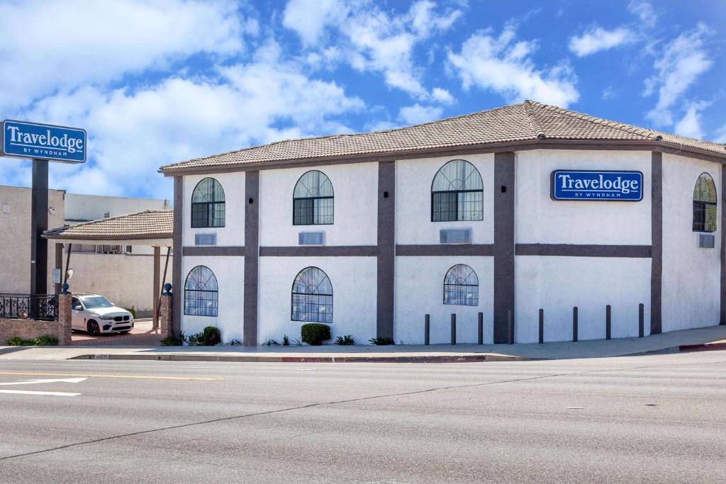 a large white building with a sign on the side of it at Travelodge by Wyndham Harbor City in Harbor City