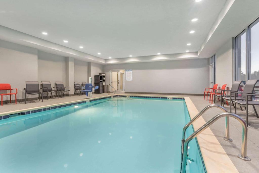 a swimming pool with chairs and a table at La Quinta Inn and Suites by Wyndham Bloomington in Bloomington