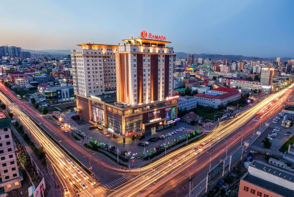 a large building with a sign on top of a city at Ramada Ulaanbaatar City Center in Ulaanbaatar