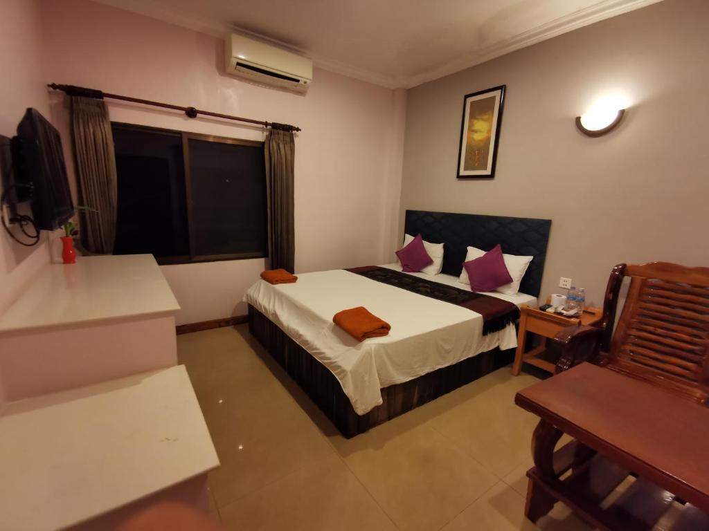 a hotel room with a bed and a table and a chair at Apex Koh Kong Hotel in Koh Kong
