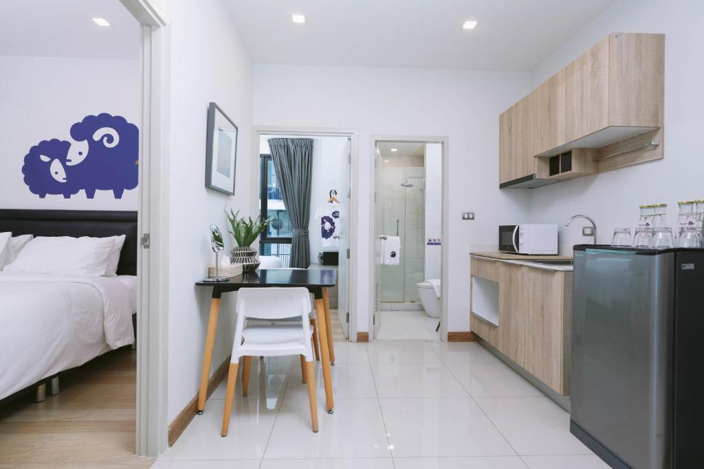 An open-plan hotel suite combines a bedroom, small dining desk, bathroom and kitchenette.