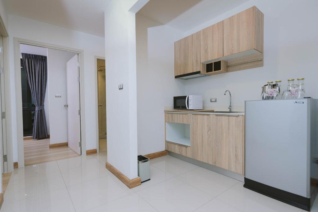 A compact kitchenette provides a sink, microwave, cabinets and refrigerator beside the room entrance.