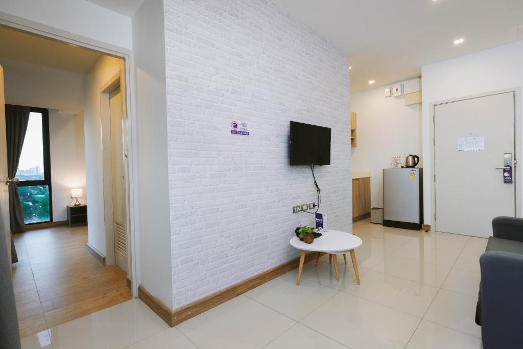A room interior with a TV wall, mini refrigerator and a glimpse toward a bright window.