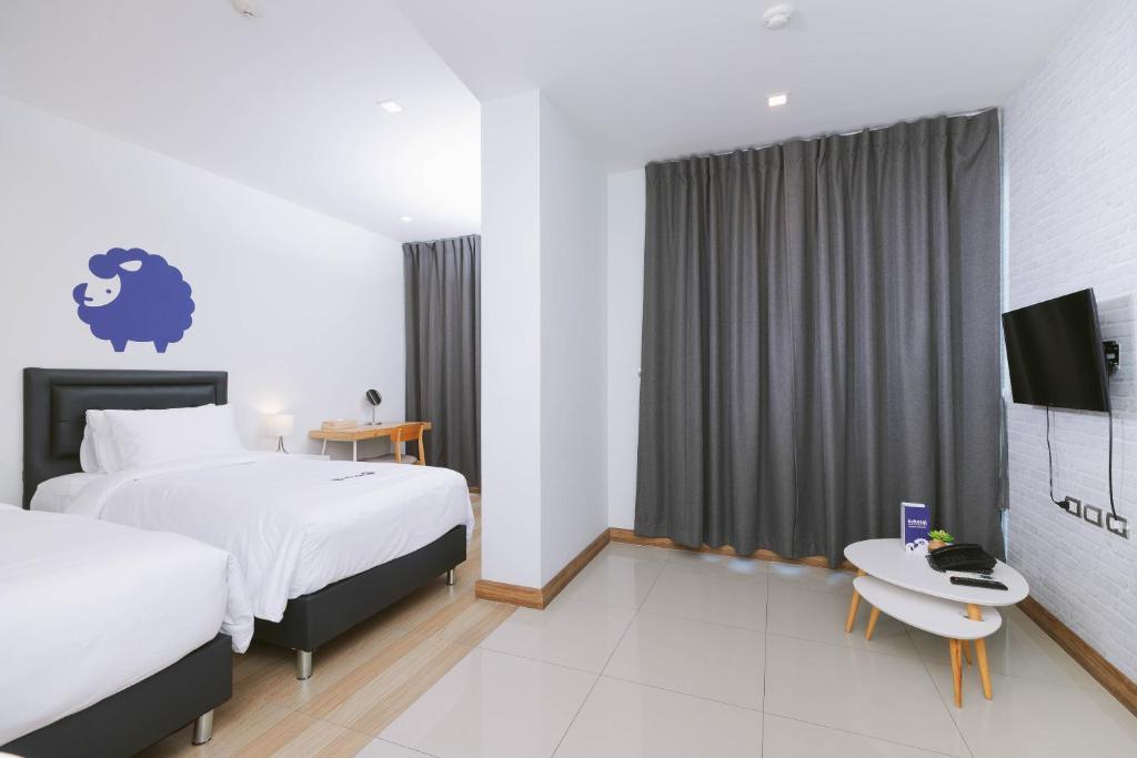 A twin room with a clear floor area, wall-mounted TV and small round table.