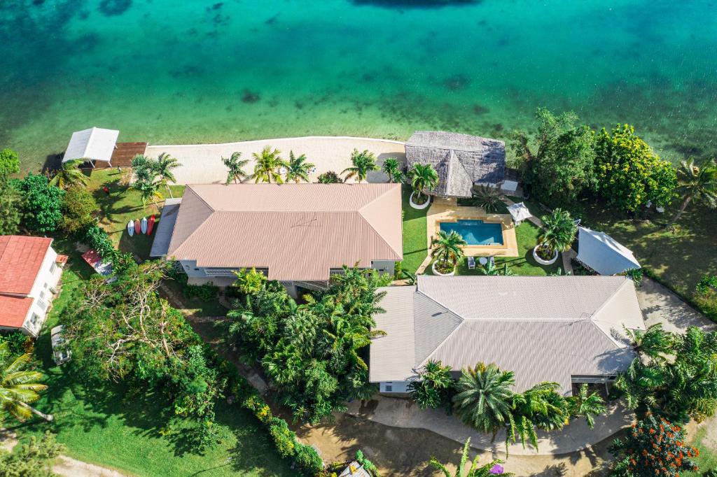 an aerial view of a house with a swimming pool and the ocean at Tropicana Lagoon Apartments in Port Vila