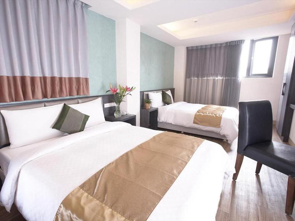 une chambre d'hôtel avec deux lits et une chaise dans l'établissement Jinbao Hotel, à Kaohsiung