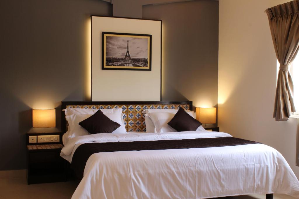 - une chambre avec un grand lit blanc et deux lampes dans l'établissement Ria Residency, à Panaji