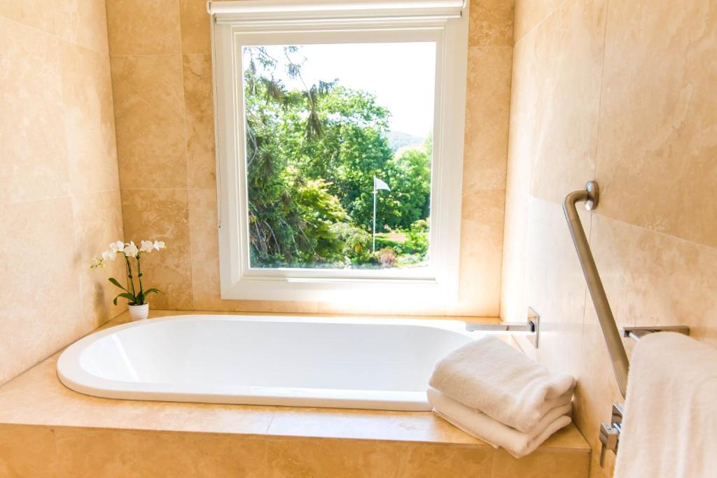 a bath tub in a bathroom with a window at Peppers Craigieburn Resort in Bowral
