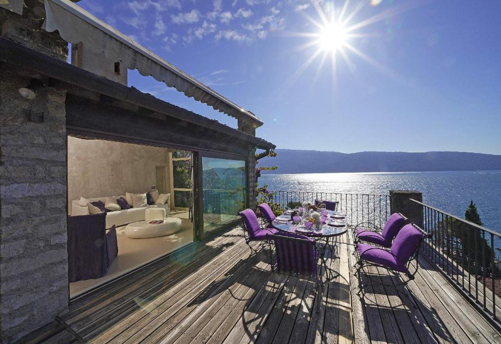 een terras met paarse stoelen en een tafel op het water bij Villa Rachele: stunning luxury villa in centre Gargnano with private pool and breathtaking views in Gargnano