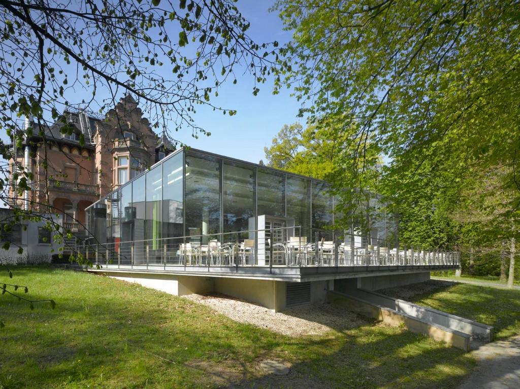 un edificio de cristal con mesas y sillas en un puente en Tagungszentrum & Hotel evangelische Akademie Bad Boll, en Göppingen