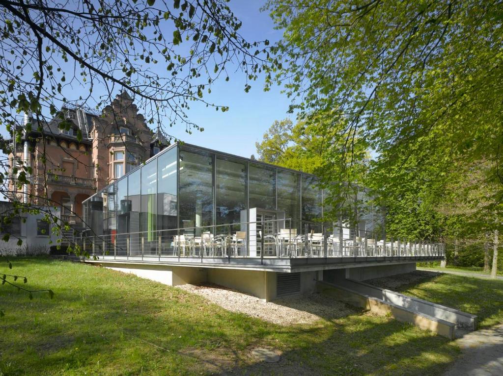 a glass building with tables and chairs on a bridge at Evangelische Tagungsstätte Bad Boll in Göppingen