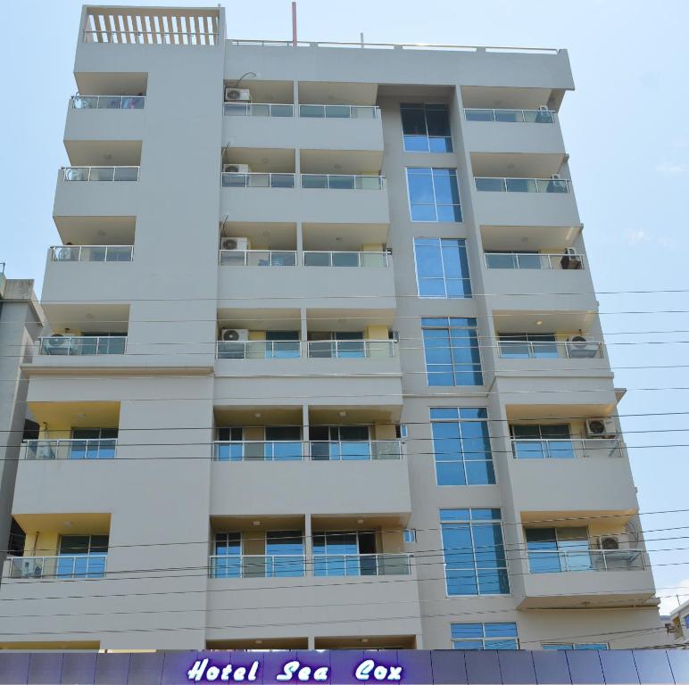 a tall white apartment building with a sign on it at Hotel Sea Cox in Cox's Bazar
