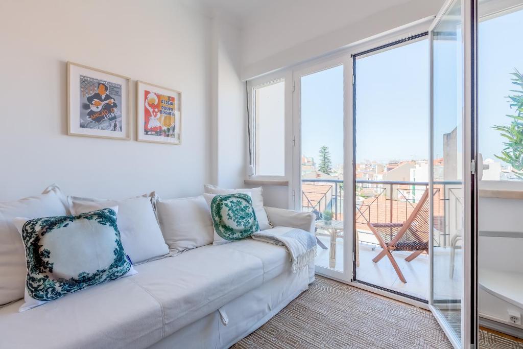 a white couch in a living room with a balcony at Renovated Sunny Apartment with Amazing Sunset Balcony , By TimeCooler in Lisbon