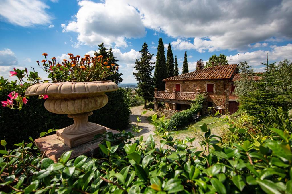 a stone bird bath with flowers in a garden at Casale Il Trecento in Castiglion Fiorentino