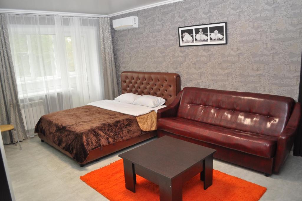 a bedroom with a bed and a leather couch at Apartments in the heart of Kursk on Radischeva street in Kursk