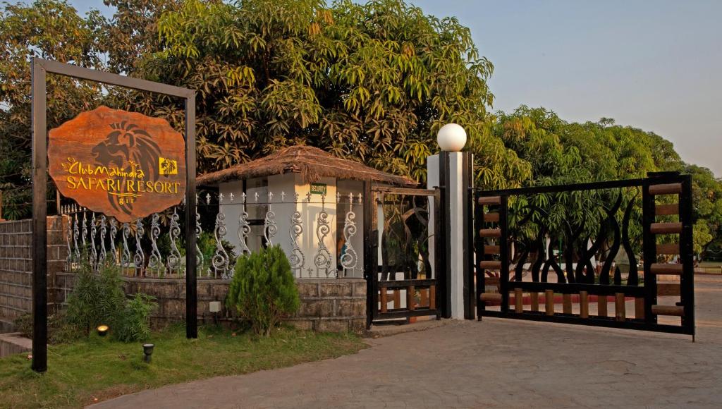 a gate with a sign on it next to a tree at Club Mahindra Sasan Gir in Sasan Gir