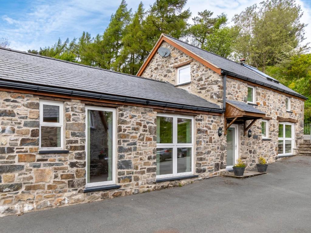 an image of a stone house with a garage at Bwthyn Clychau'r Gog in Clawdd-newydd