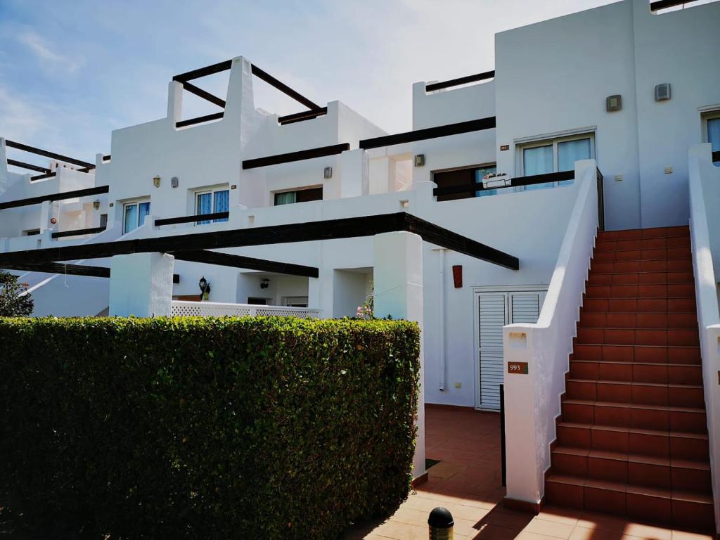 ein weißes Gebäude mit Treppen und einer Hecke in der Unterkunft 2 Bedroom Apartment Condado de Alhama in Alhama de Murcia