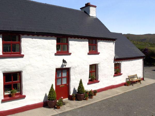 a white building with red windows and a black roof at Fehanaugh Cottage in Atadav Bridge