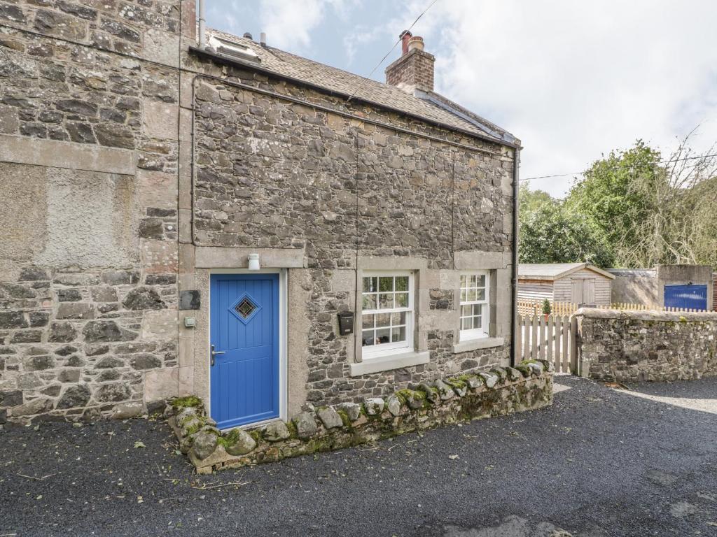 an old stone house with a blue door at Kirk Cottage in Hownam